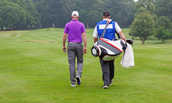 Golfer and caddy walking up a fairway